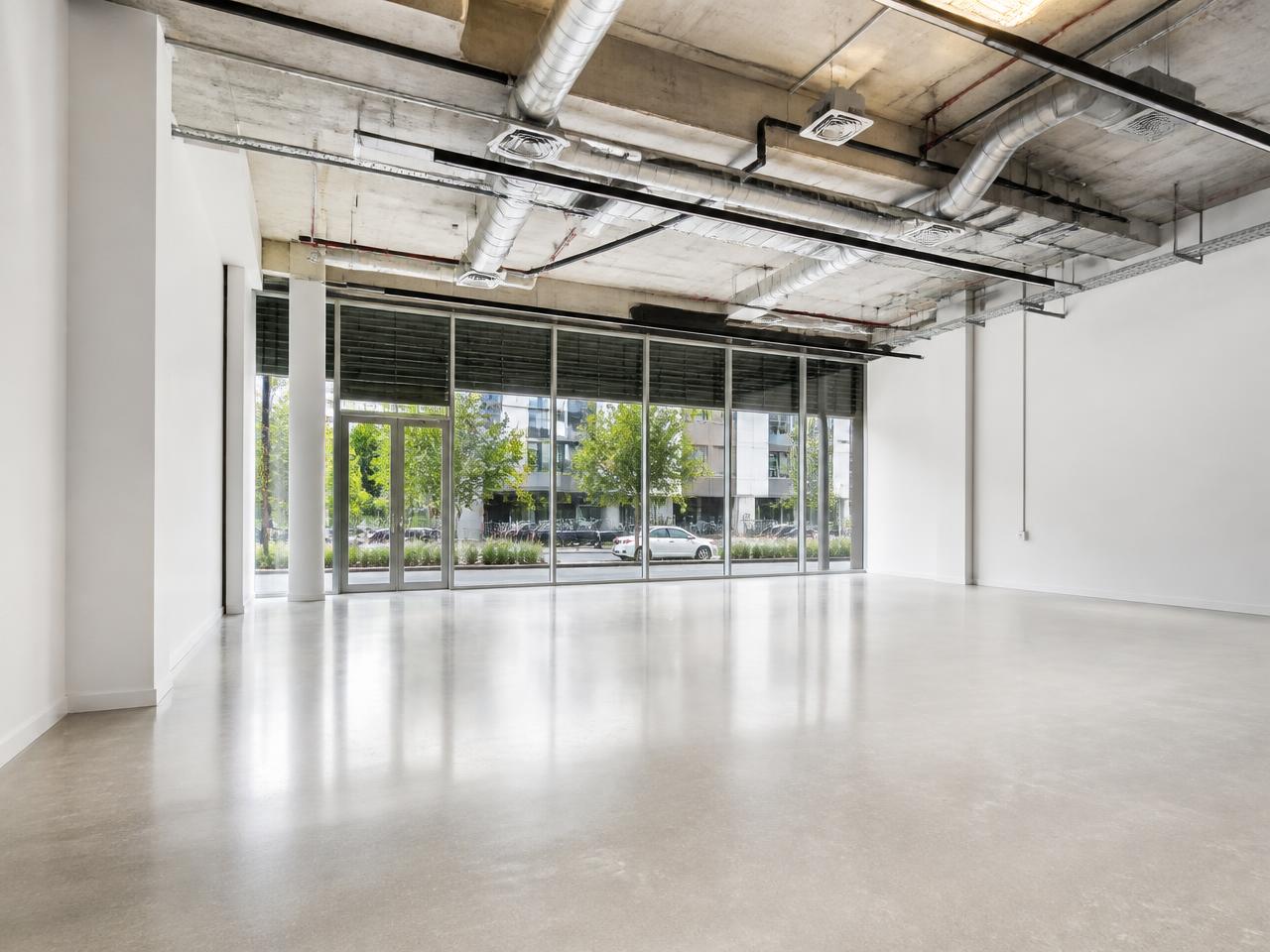 Empty commercial tenancy interior with polished concrete floor and floor-to-ceiling glazing.