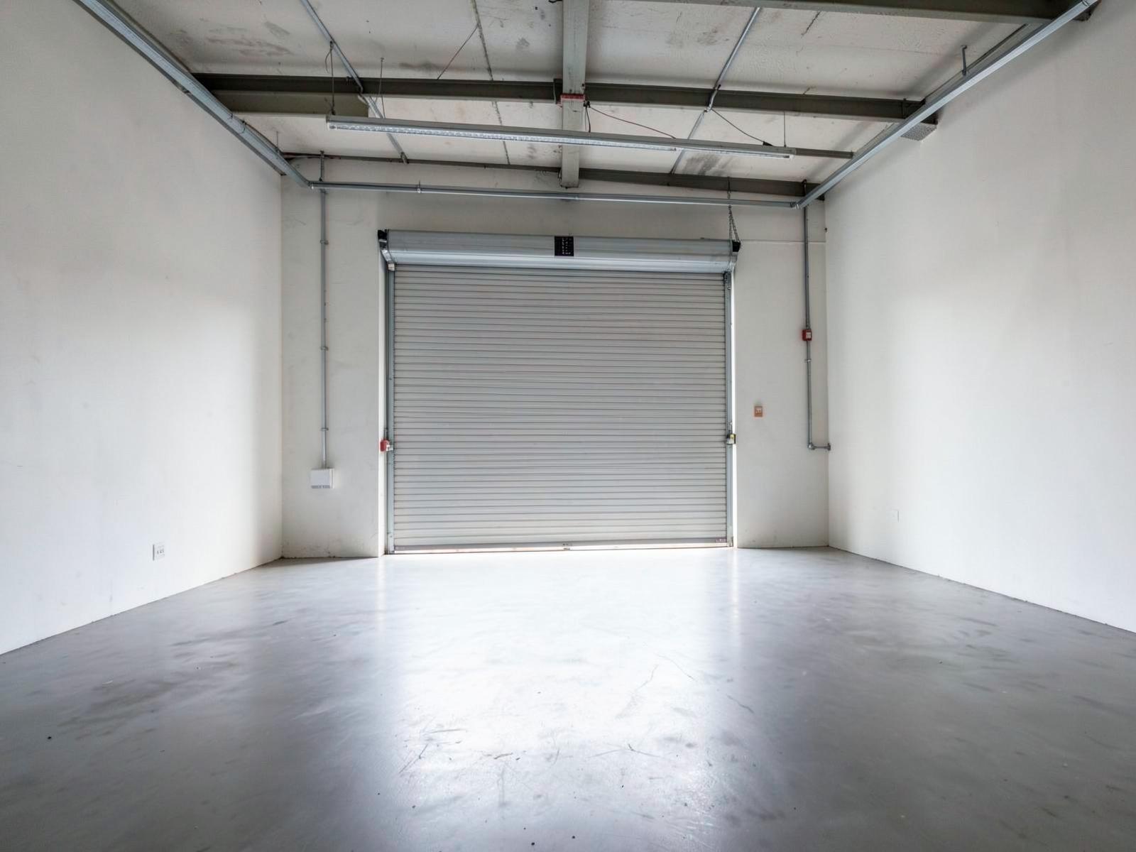 Empty light-industrial workshop unit with a roller door and clean floor.