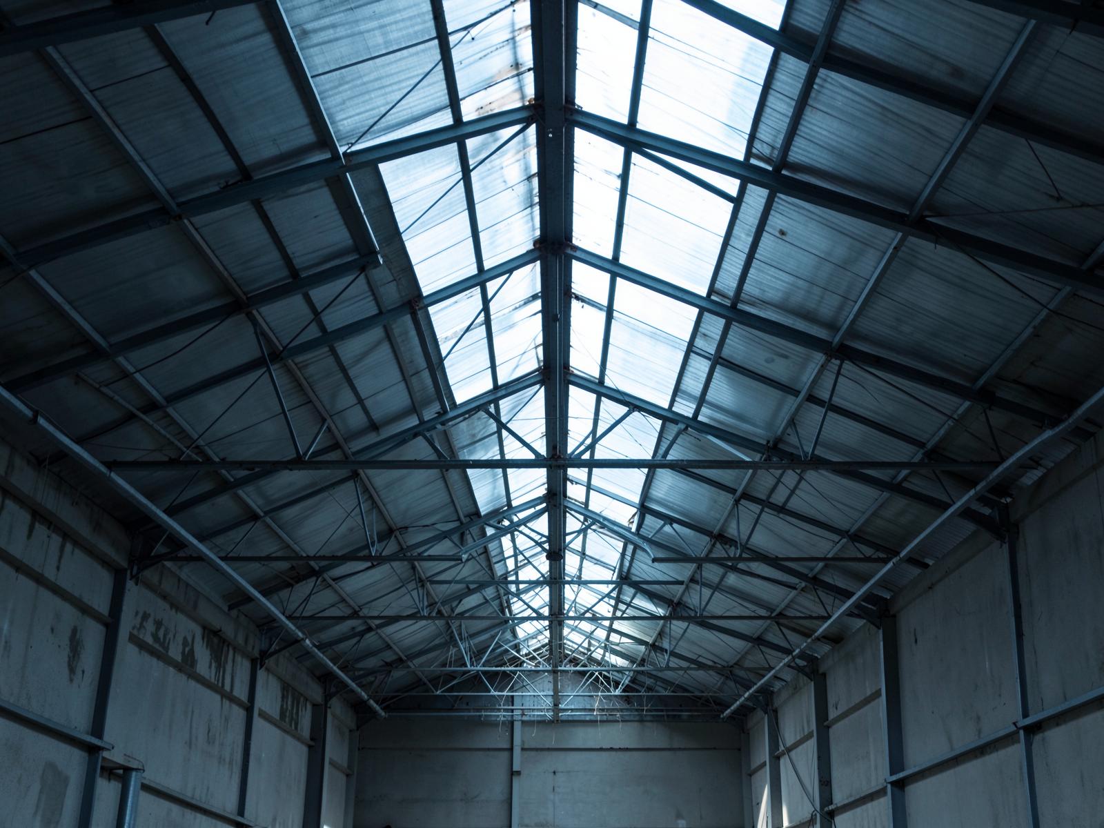 Exposed steel roof structure inside an empty industrial building.