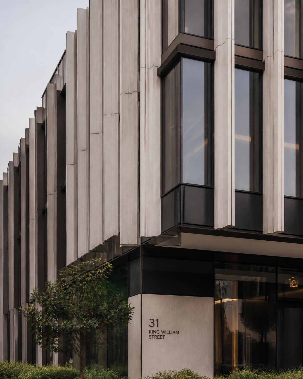 Modern commercial building facade with vertical concrete fins and dark glazing.