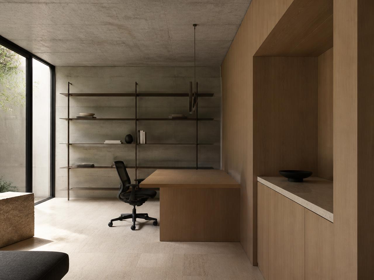 Calm advisory office interior with board-formed concrete walls, a timber desk and slim steel shelving in daylight.
