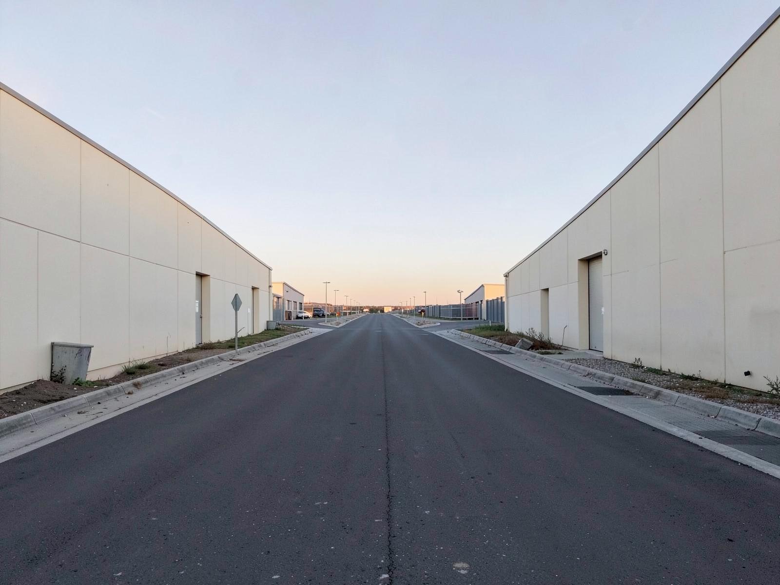 Access road through an industrial estate in soft late light.