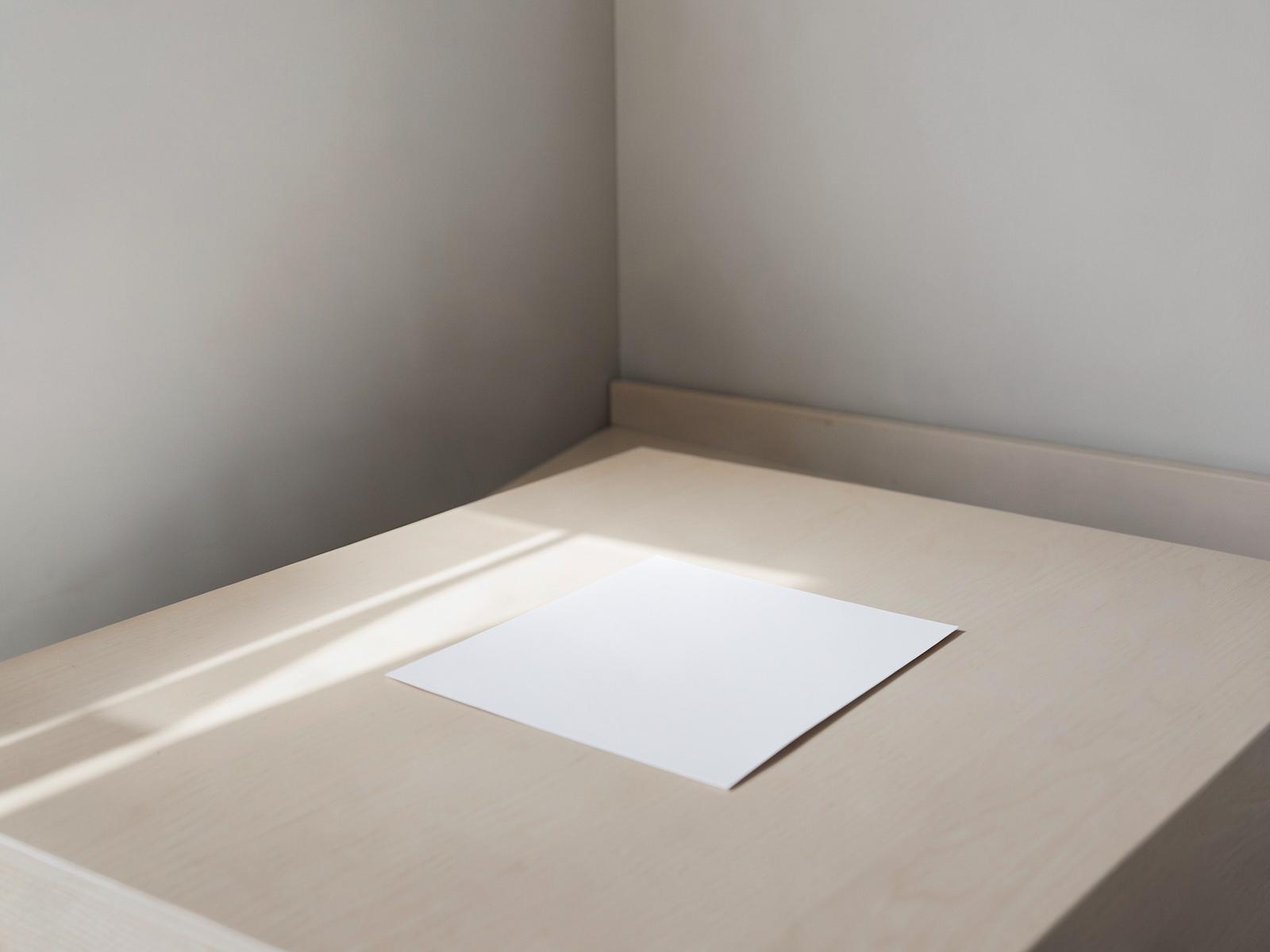Empty meeting table with a single blank sheet in morning light.