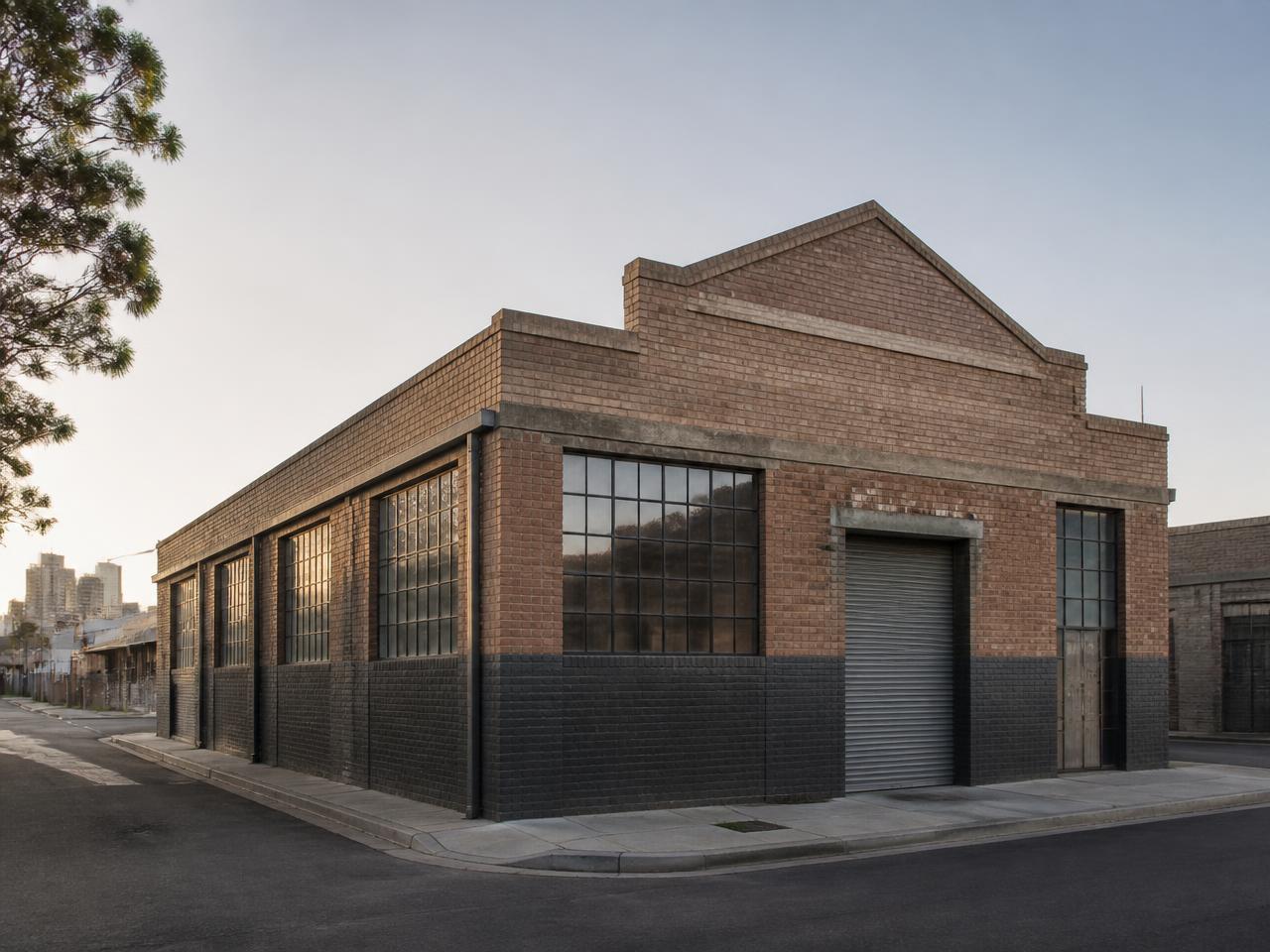 Corner warehouse in a transitioning industrial precinct, late afternoon light.